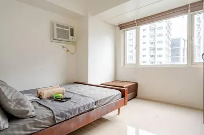 a small bedroom with a bed and a window at 2Bedroom 2Bath near moa with Balcony facing pool in Manila