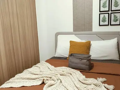 a bed with a blanket and a bag on it at Heart of Mall of Asia - Aseana Pasay in Manila