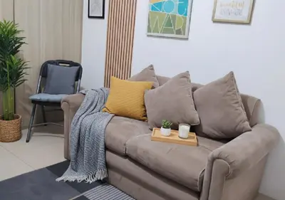 a living room with a brown couch with yellow pillows at Mall of Asia - Aseana Pasay Cheap Accommodation in Manila