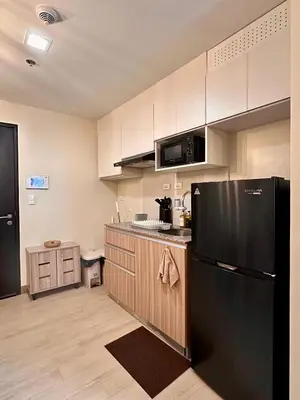 a kitchen with a black refrigerator and wooden cabinets at The Verdin in General Trias