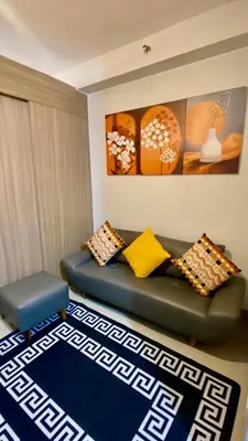 a living room with a green couch and a blue rug at CASA ROSITA Staycation by 3MR in Manila