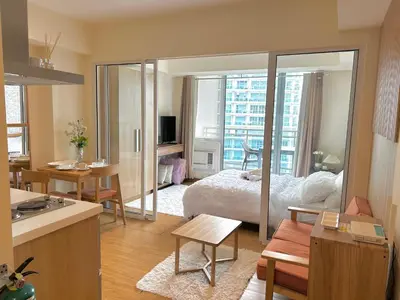 a living room with a bed and a kitchen with a kitchen at M&M Azure Staycation Parañaque in Manila