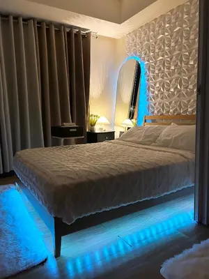 a bedroom with a large bed with blue lighting at M&M Azure Staycation Parañaque in Manila