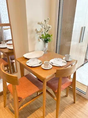a wooden table with two chairs and a vase with flowers at M&M Azure Staycation Parañaque in Manila