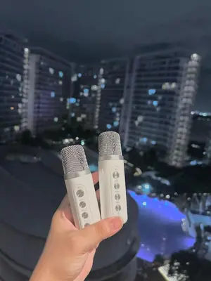 a person holding a microphone in front of a city at M&M Azure Staycation Parañaque in Manila