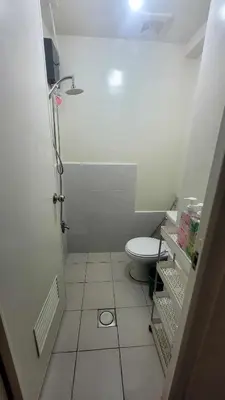 a small bathroom with a toilet and a tiled floor at Richard's Pad in Manila