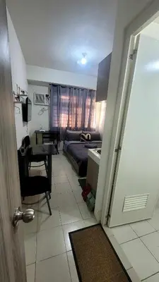 a living room with a bed and a table and a door at Richard's Pad in Manila