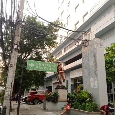 a statue in front of a building with a street sign at Sweet Stay at Manila in Manila