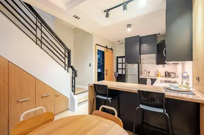 a kitchen with black cabinets and a counter with a bar at MUJI TOWNHOUSE SUITE in Central Makati BILLIARDS, KTV in Manila