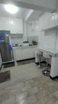 a kitchen with white cabinets and a table and a refrigerator at 2BR ENTIRE Familyhome near NAIA,MOA,BGC in Manila