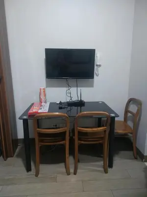 a black table with two chairs and a television on a wall at Ezekiel's Suites in Manila