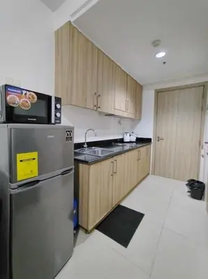 a kitchen with a stainless steel refrigerator and wooden cabinets at Shore Residences Tower D - 2 Bunkbed Ideal for 6 guests in Manila