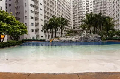 a large swimming pool with palm trees and buildings at Shore Residences Tower D - 2 Bunkbed Ideal for 6 guests in Manila