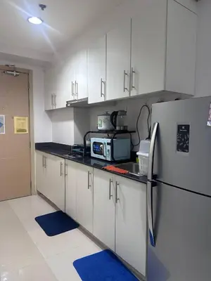 a kitchen with white cabinets and a refrigerator at Sea Residences Tower D, by Richnells in Manila