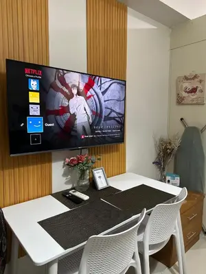 a tv on a wall above a table with chairs at Sea Residences Tower D, by Richnells in Manila