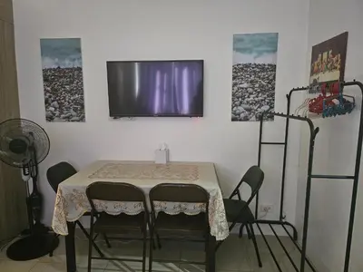 a table with chairs and a television on a wall at BIG CUT, END UNIT in SHORE RESIDENCES in Manila
