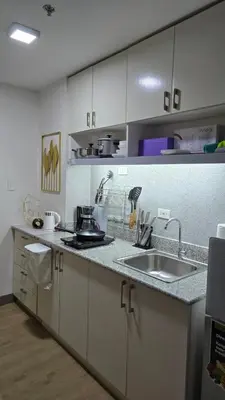 a kitchen with white cabinets and a sink at SMDC Spring Resort Residences in Manila