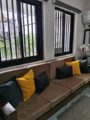 a brown couch with yellow and blue pillows on it at Samong Transient House in Imus