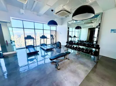a gym with several exercise equipment in a room with windows at Rockwell View Acqua Iguazu Tower 17th flr Mandaluyong-Makati 1BR in Manila
