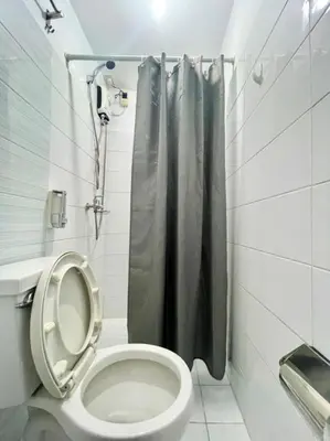 a bathroom with a toilet with a shower curtain at Cedar House in Manila