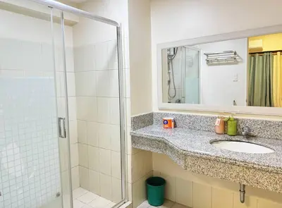 a bathroom with a sink and a shower with a mirror at \u9a6c\u5c3c\u62c9\u6e7e\u4e09\u623f\u516c\u5bd3 in Manila