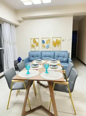 a living room with a table and a blue couch at \u9a6c\u5c3c\u62c9\u6e7e\u4e09\u623f\u516c\u5bd3 in Manila