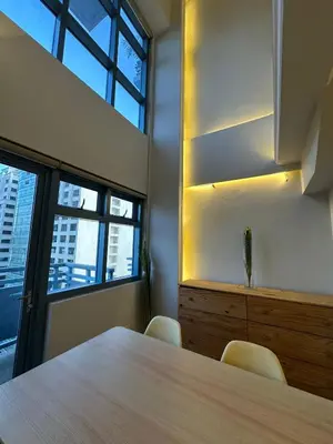 a meeting room with a wooden table and a window at Newly Renovated 2-Storey Loft at Greenbelt 1 in Manila