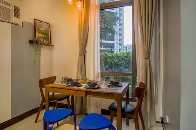 a dining room table with blue chairs and a window at Vintage Mickey Disney Stay in BGC -200mbps wifi in Manila