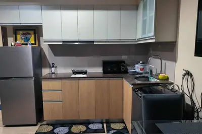 a small kitchen with a refrigerator and a stove at Studio Type Condotel at Venice McKinley Taguig City in Manila