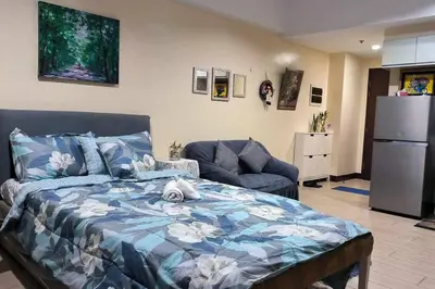 a bedroom with a bed and a refrigerator and a couch at Studio Type Condotel at Venice McKinley Taguig City in Manila