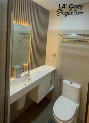 a bathroom with a toilet and a sink and a mirror at Smdc Coast Residences- LA Cozy Staycation in Manila