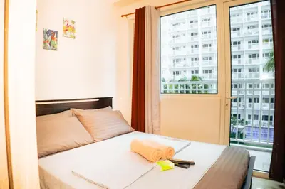 a bedroom with a bed and a window with a building at 1bedroom with Balcony facing pool Near MOA in Manila