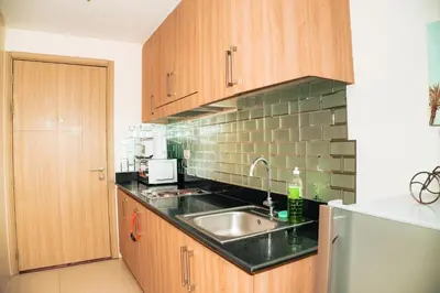 a kitchen with wooden cabinets and a sink at 1bedroom with Balcony facing pool Near MOA in Manila