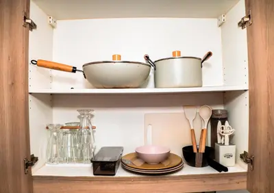 a cupboard with dishes and utensils in it at 1bedroom with Balcony facing pool Near MOA in Manila