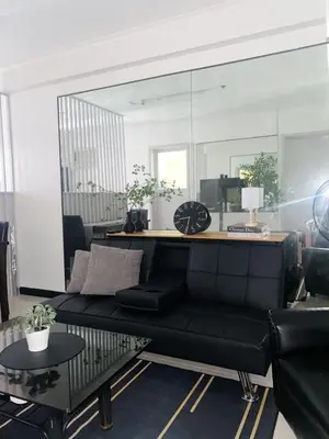 a living room with a black couch and a mirror at A-South of Market SOMA in Manila