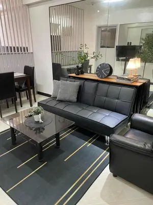 a living room with a black couch and a table at A-South of Market SOMA in Manila
