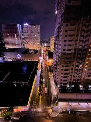 a city street at night with tall buildings at Deryll's Fun house in Manila
