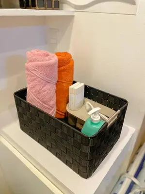 a black basket sitting on a shelf with towels at Deryll's Fun house in Manila