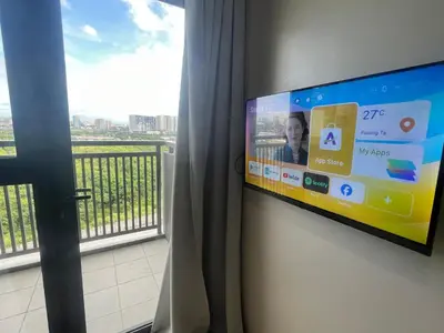 a flat screen tv hanging on a wall next to a window at Gentry Manor Balcony Green View WiFi Netflix Walk to Okada Casino 8J in Manila