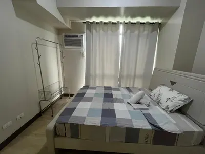 a bedroom with a bed with a checkered blanket at Gentry Manor Balcony Green View WiFi Netflix Walk to Okada Casino 8J in Manila