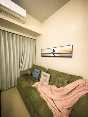 a living room with a green couch with a blanket at Luxury 1 Bedroom across Okada II Balcony w View in Manila