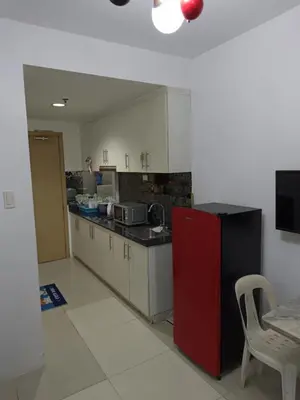 a kitchen with a red refrigerator and white cabinets at Alley condotel Sea Residence in Manila