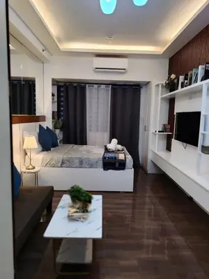 a bedroom with a bed and a living room at Affordable Modern Studio with Netflix WiFi Balcony in Air Residences in Manila