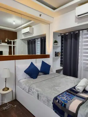 a bedroom with a large bed with blue pillows at Affordable Modern Studio with Netflix WiFi Balcony in Air Residences in Manila