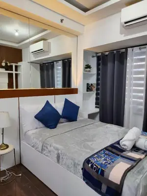 a bedroom with a large bed with blue pillows at Affordable Modern Studio with Netflix WiFi Balcony in Air Residences in Manila