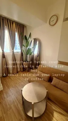 a living room with a couch and a table and a clock at Tahanan - Victoria de Makati in Manila