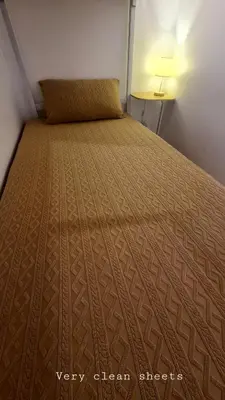 a bed in a small room with a large bedsheet at Tahanan - Victoria de Makati in Manila
