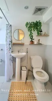 a bathroom with a toilet and a sink and a mirror at Tahanan - Victoria de Makati in Manila