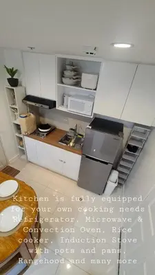a kitchen with white cabinets and a counter top at Tahanan - Victoria de Makati in Manila