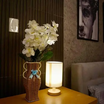a vase of flowers on a table with a lamp at Gabila Staycation at Azure in Manila